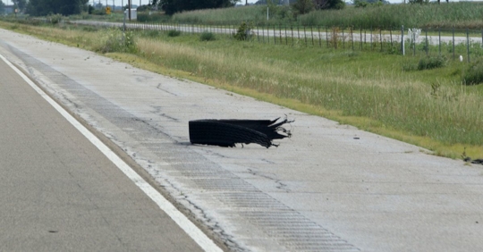 Blown tire on the side of the highway.