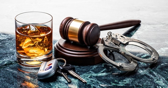 Glass of brown liquor, a gavel, handcuffs, and car keys.